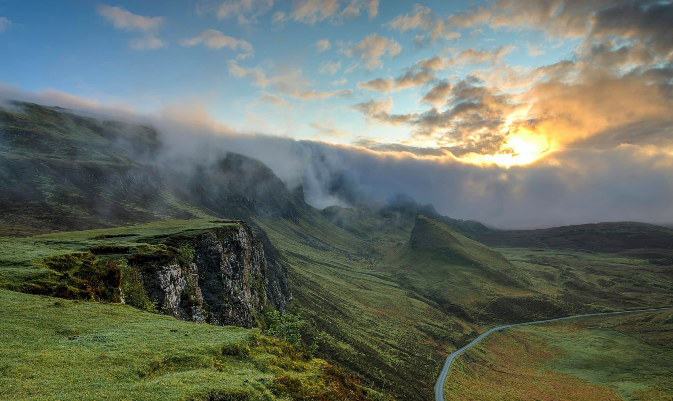 A green mountain ridge at dawn with rolling fog